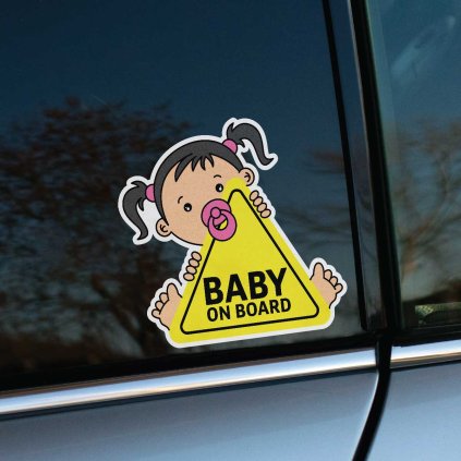 Tlačená nálepka “Baby on Board” s motívom dievčatka s tmavými copíkmi a ružovým cumlíkom, držiaceho žltý výstražný trojuholník.