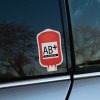 Tlačená nálepka v tvare krvného vaku s textom AB+ Rh POSITIVE, ideálna na auto, prilbu alebo batožinu pre rýchlu zdravotnú identifikáciu.