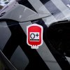 Tlačená nálepka v tvare krvného vaku s textom 0+ Rh POSITIVE, určená na prilbu, auto alebo batožinu pre jasné označenie krvnej skupiny.