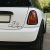 Plotrovaná nálepka na auto s hladnou mačkou pri prázdnej miske, vtipný jednofarebný motív v štýle Simon’s Cat.