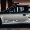 Plotrovaná nálepka s nápisom „Passat“ v elegantnom písme na dvere auta.