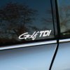 Plotrovaná nálepka s nápisom „Golf TDI“ v dynamickom a technickom písme na bočné okno auta.