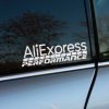 Nálepka "AliExpress Performance" nalepená na bočnom okne auta, s výrazným bielym textom a dynamickým dizajnom pripomínajúcim rýchlosť a výkon. Táto nálepka je ideálna pre fanúšikov úprav a tuningu vozidiel, ktorí hľadajú cenovo dostupné diely a doplnky na zvýšenie výkonu a štýlu svojho auta. Moderný a športový vzhľad dodáva vozidlu osobitý charakter.
