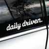 Biela nálepka s nápisom "daily driven." nalepená na okne bieleho auta. Táto nálepka s jednoduchým a čistým dizajnom vyjadruje, že auto je využívané každý deň. Ideálny doplnok pre vodičov, ktorí chcú zdôrazniť svoju vášeň pre jazdu a pravidelné využívanie svojho vozidla. Štýlový detail, ktorý pridáva osobitosť a zvýrazňuje praktickosť majiteľa auta.