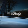 Plotrovaná nálepka "OnlySlowly" v bielej farbe, minimalistický vtipný textový motív s elegantným písmom a symbolom zámku, nálepka na auto.