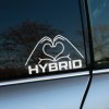 Na obrázku vidíme nálepku na bočnom okne auta s nápisom "HYBRID". Dve ruky formujúce srdce sú umiestnené nad slovom "HYBRID", čo pridáva nálepke jedinečný a moderný vzhľad. Tento dizajn je ideálny pre majiteľov hybridných vozidiel, ktorí chcú svojmu autu dodať osobitý dotyk. Nálepka nielen zlepšuje estetiku vášho auta, ale aj vyjadruje vašu podporu pre ekologické a udržateľné technológie. Je to perfektný doplnok pre každého, kto chce zdôrazniť svoju lásku k hybridným technológiám a spraviť svoje auto ešte výnimočnejším na cestách.