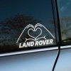 Na obrázku je originálna nálepka na bočnom okne vozidla Land Rover, zobrazujúca dve ruky formujúce srdce nad nápisom "LAND ROVER". Tento jedinečný a kreatívny dizajn je ideálny pre všetkých majiteľov Land Rover, ktorí chcú pridať svojmu autu osobitý dotyk. Nálepka symbolizuje vášeň a lásku k značke, čím sa váš Land Rover odlíši od ostatných vozidiel na cestách. Elegantný dizajn dodáva vozidlu jedinečný štýl a vizuálne zaujme každého okoloidúceho. Perfektný spôsob, ako prejaviť svoju oddanosť tejto prestížnej značke.