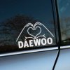 Biela nálepka na bočnom okne auta zobrazuje ruky tvoriace tvar srdca nad nápisom "DAEWOO". Táto nálepka vyjadruje majiteľovu lásku k svojej značke auta a pridáva vozidlu osobitý a vkusný vzhľad. Ideálny doplnok pre všetkých fanúšikov značky Daewoo, ktorí chcú svojmu autu dodať trochu sentimentálnej a estetickej hodnoty. Nálepka je jednoduchá, no výrazná, čo z nej robí perfektný spôsob, ako personalizovať svoje auto pomocou nálepiek na auto.