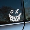 Plotrovaná nálepka na auto s úsmevom plným ostrých zubov a očami v tvare O a X v štýle ručne kresleného graffiti.