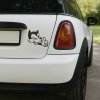 Plotrovaná nálepka na auto s retro mačacou postavičkou v cartoon štýle, ktorá žmurká a ukazuje palec hore.