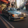 Mercedes-Benz W124 zaparkovaný v japonskej ulici, čelné sklo zdobí nápis v katakane s automobilovým motívom.