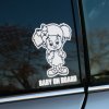 Plotrovaná nálepka na auto s motívom dievčatka s mašľou a vrkôčikmi, stojaceho v šatách, doplnená o text BABY ON BOARD.
