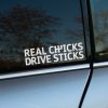 Plotrovaná nálepka na auto s textom „REAL CHICKS DRIVE STICKS“ a ikonickým symbolom manuálnej radiacej páky.