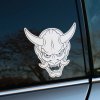 Plotrovaná nálepka na auto s motívom japonskej oni masky s rozzúreným výrazom, výraznými rohmi a detailnými líniami.