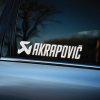 Plotrovaná nálepka s logom a nápisom „Akrapovič“ v športovom dizajne, určená pre fanúšikov výfukových systémov a tuningu.
