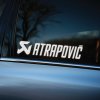 Plotrovaná nálepka s logom a nápisom „Atrapovič“ v štýlovom športovom prevedení, zvýrazňujúca tuningový charakter vozidla.