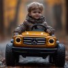 Chlapec v hnedej bunde sedí za volantom žltého detského Mercedesu a jazdí po úzkej ceste pokrytej jesennými listami.