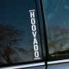 Nálepka s vertikálnym nápisom „HOOVADO“ v modernom, čistom písme, nalepená na okne sivého auta. Biela farba písma výrazne kontrastuje s tmavým sklom, čím vytvára minimalistický a odvážny vzhľad. Tento dizajn je ideálny pre tých, ktorí chcú pridať svojmu vozidlu jedinečný a výrazný prvok, ktorý púta pozornosť svojou jednoduchosťou a štýlovosťou.