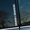 Plotrovaná nálepka HOONIGAN v zvislom formáte s rámčekom, ikonická nálepka na auto pre milovníkov agresívnej jazdy.