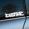 Plotrovaná nálepka pozostávajúca z nápisu v hrubom umeleckom graffiti štýle, ktorý uvádza presný text v znení DUSTER.