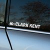 Plotrovaná nálepka na auto s menom „Clark Kent“ a symbolom kvapky krvi s krvným typom 0− v jednoduchom bezpätkovom písme.