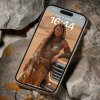 iPhone položený na skalách zobrazuje na uzamknutej obrazovke ženu v tradičnom púštnom oblečení vedľa SUV v piesočných dunách.