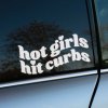 Plotrovaná nálepka na auto s nápisom „hot girls hit curbs“ v zaoblenom písme so srdiečkami namiesto bodiek.