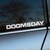 Plotrovaná nálepka s logom Doomsday v jednoduchom blokovom písme.