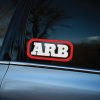 Plotrovaná dvojfarebná nálepka na auto s logom ARB v bielych písmenách a červenom rámiku so zaoblenými rohmi.