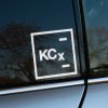 Plotrovaná nálepka na auto s logom KCX, minimalistický hranatý dizajn s textom v ráme a dvoma horizontálnymi čiarami.