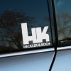 Plotrovaná nálepka na auto s logom Heckler & Koch, masívne iniciály HK s čistým nápisom pod nimi v modernom štýle.