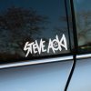 Plotrovaná nálepka „Steve Aoki“ s typickým logom a smajlíkom s prekríženými očami, energická nálepka na auto pre fanúšikov EDM.