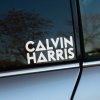 Plotrovaná nálepka „Calvin Harris“ s geometrickými prvkami v texte, moderná nálepka na auto pre fanúšikov elektronickej hudby.
