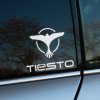 Plotrovaná nálepka „Tiesto“ s ikonickým logom vtáka a futuristickým fontom, štýlová hudobná nálepka na auto.