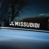 Plotrovaná nálepka na auto s bielym nápisom „MISSUBIBI“ a logom Mitsubishi ako vtipná paródia známej automobilovej značky.