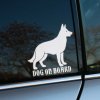 Plotrovaná nálepka na auto s charakteristickým obrysom nemeckého ovčiaka a anglickým textom „Dog on Board“.