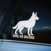 Plotrovaná nálepka na auto s majestátnym obrysom vlčiaka a anglickým textom „Dog on Board“, vhodná na zadné sklo.