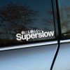 Plotrovaná nálepka na auto s textom „Superslow“ a japonským nápisom nad ním, v štýle JDM a minimalistického tuningu.