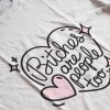 Potlač na tričku s čiernym nápisom „Bitches are people too.“ v ružovom srdci s hviezdičkami. Biele tričko s potlačou.