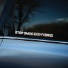 Plotrovaná nálepka s textom STOP SMOG GO HYBRID vo veľkých bielych písmenách, určená na podporu ekologickej jazdy.