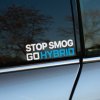 Plotrovaná nálepka s dvojriadkovým textom STOP SMOG GO HYBRID, biele a modré písmo, ekologický motív na podporu hybridných áut.