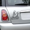 Plotrovaná nálepka s ilustráciou usmiateho plemena Welsh Corgi vyzerajúceho spoza hrany a nápisom v elegantnom písanom písme v znení Dog On Board.