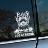 Plotrovaná nálepka s motívom teriéra držiaceho tabuľku s nápisom „Dog on board“, určená pre milovníkov psov.