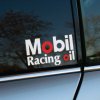Plotrovaná nálepka s logom Mobil Racing Oil, s červeným zvýraznením písmen O v slovách „Mobil“ a „oil“.