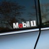 Plotrovaná nálepka s logom Mobil 1, s červeným zvýraznením písmena O a bielym štvorcom s číslom 1 na konci nápisu.