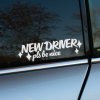 Plotrovaná nálepka s textom New Driver pls be nice a dekoratívnymi hviezdičkami, typografický motív pre nálepka na auto