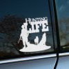 Plotrovaná nálepka HUNTING LIFE, vyrezávaná silueta poľovníka so zbraňou a dvoch psov pod veľkým nápisom v pozadí.