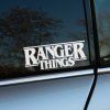 Plotrovaná nálepka s nápisom „RANGER THINGS" v štýle loga Stranger Things s vodorovnými linkami nad a pod textom.