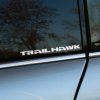 Plotrovaná nálepka s textom TRAILHAWK v hrubých tehnických písmenách, model vozidla Jeep.