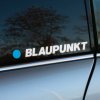 Tlačená nálepka na auto s logom BLAUPUNKT, výrazný modrý kruh vľavo od nápisu v naklonenom tučnom fonte.